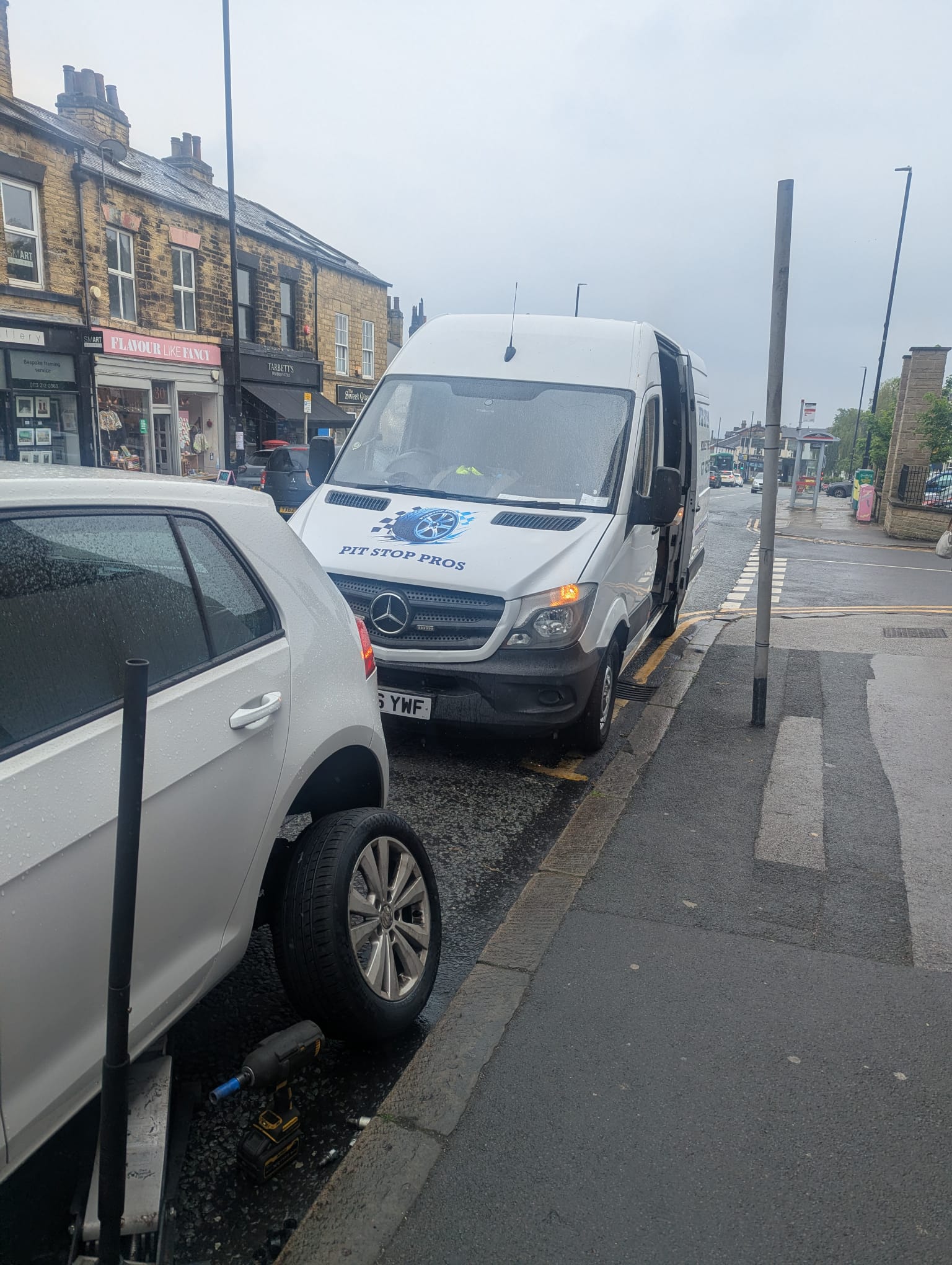 Mercedes hatchback raised on a jack on a busy shopping street